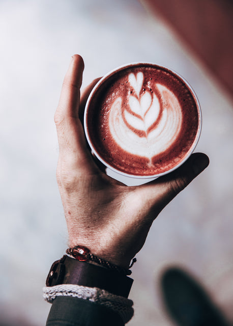 Latte Art Getränk in der Hand von oben fotografiert. 